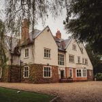 Historic country house surrounded by ivy and trees.