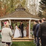 Outdoor wedding ceremony under a wooden gazebo.