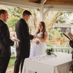 Couple exchanging rings at outdoor wedding ceremony.