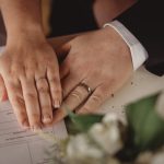 Couple's hands with wedding rings on document