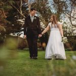 Couple holding hands outdoors, bride in wedding dress.