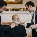 Two men shaving another man's face.