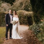 Bride and groom in elegant garden setting.