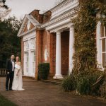 Couple posing outside a classic brick mansion