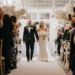 Bride and groom walking down the aisle, guests applauding.