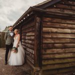 Bride and groom beside rustic wooden building