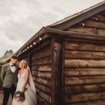 Bride and groom by rustic wooden building