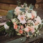 Pink and white flower bouquet on wooden beam.