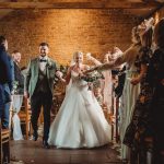 Bride and groom walk through confetti-filled aisle.