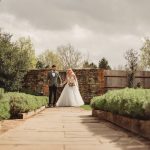 Bride and groom walking in garden wedding setting.