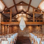 Wedding dress hanging in rustic barn venue.