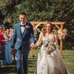 Happy couple walking down the wedding aisle outdoors.