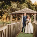 Bride and groom by wooden gazebo in garden