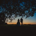 Silhouette of couple under tree at sunset