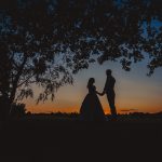 Silhouette couple holding hands at sunset.