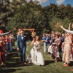 Bride and groom walk through cheering wedding guests.