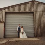 Couple in wedding attire by wooden barn