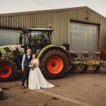 Couple in wedding attire by green tractor