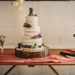 Three-tier wedding cake with flowers and wellies topper.