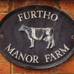 Furtho Manor Farm sign on brick wall.