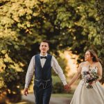 Bride and groom walking hand in hand outdoors.