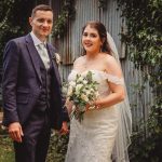 Bride and groom smiling in garden setting.