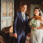 Bride and groom holding hands in rustic setting.