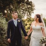 Bride and groom walking outdoors, holding hands.