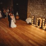 Wedding couple's first dance under 'LOVE' sign.