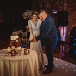 Couple cutting wedding cake with sword.