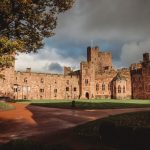 Historic castle with cloudy sky and autumn trees.