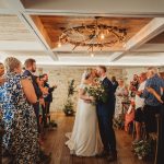 Bride and groom kissing at indoor wedding ceremony.