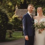 Bride and groom smiling outdoors in wedding attire.