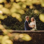 Bride and groom smiling on a stone bridge.