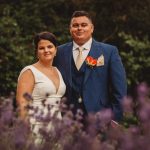 Couple smiling in garden, blurred lavender foreground.