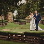 Bride walks with father in garden ceremony