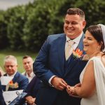 Happy couple exchanging vows at outdoor wedding ceremony.