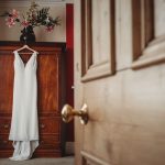 White wedding dress hung on wooden wardrobe