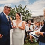 Outdoor wedding ceremony with happy couple exchanging rings.