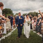 Bride and groom walking through confetti at wedding.