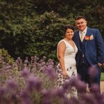 Couple in garden, purple flowers foreground.