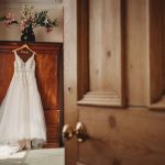 Wedding dress hanging on wooden wardrobe.