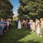 Newlyweds walking through confetti shower, outdoors ceremony.