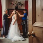 Bride getting ready, assisted by two women.