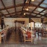 Rustic wedding reception with fairy lights and long tables.