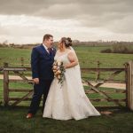 Bride and groom laughing in countryside setting.