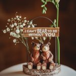 Two bear figurines with love quote and flowers.