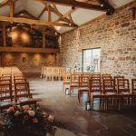 Rustic wedding venue with wooden chairs and stone walls.