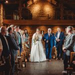 Bride walking down the aisle in rustic venue.