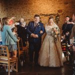 Couple celebrates wedding with confetti and guests applauding.